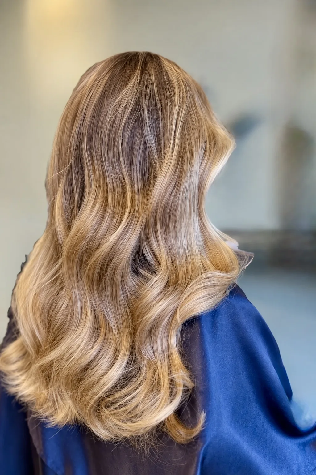 Back view of a long blonde balayage human-hair wig with soft waves