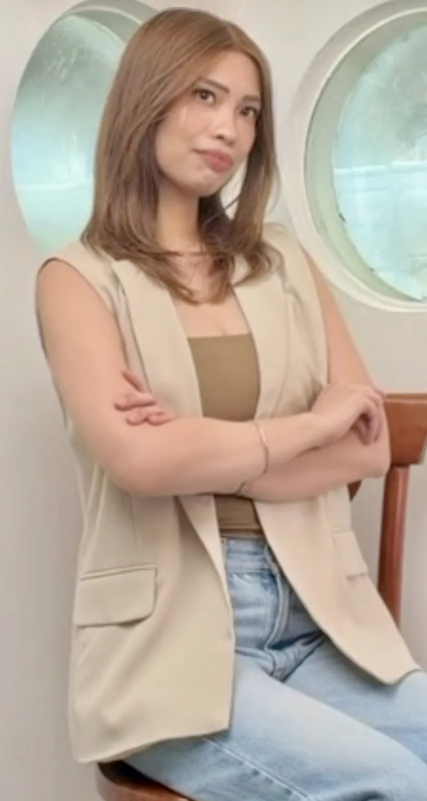 HEADS Brand Ambassador seated in a beige vest wearing a copper shoulder-length human-hair wig