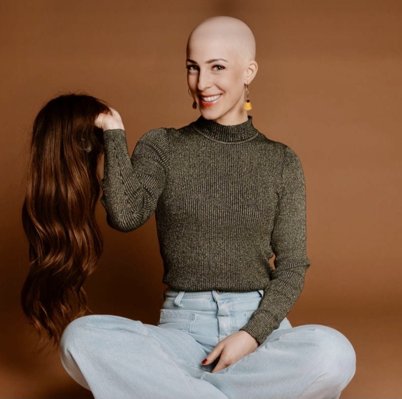 HEADS client without hair holding her human hair wig in her hands in the studio