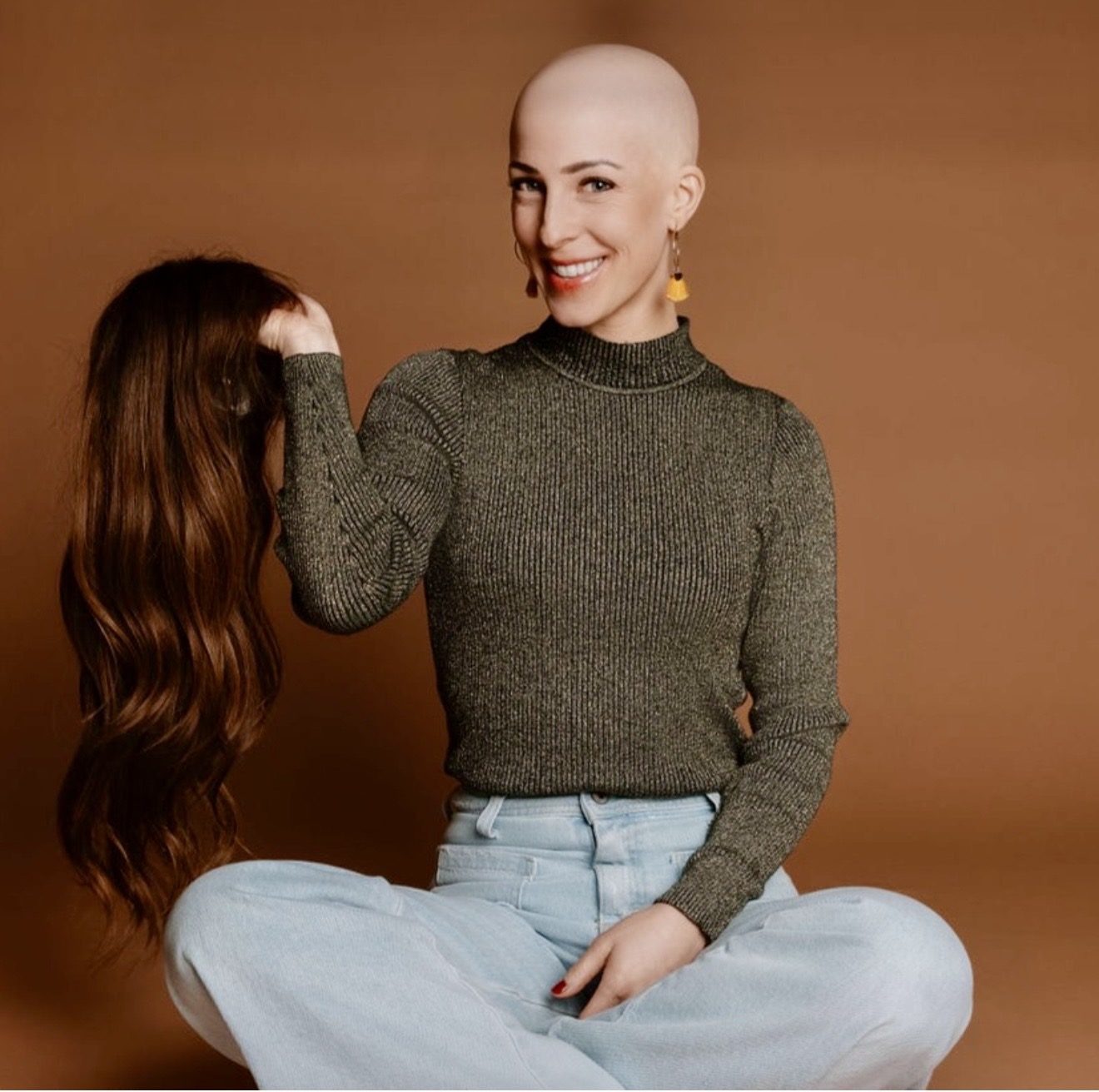 HEADS client without hair holding her human hair wig in her hands in the studio