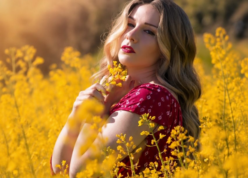 The same woman wearing her HEADS human-hair wig in a field of yellow flowers