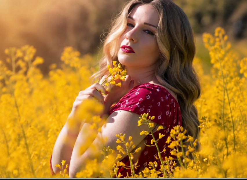 The same woman wearing her HEADS human-hair wig in a field of yellow flowers